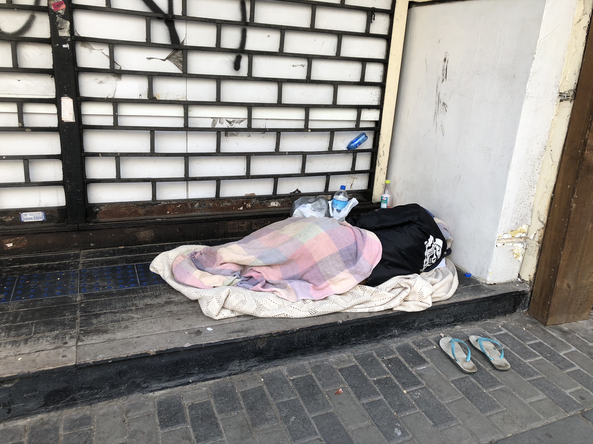 Cuidado frágil: um morador de rua dorme em uma calçada de uma metrópole brasileira. Foto: RPB