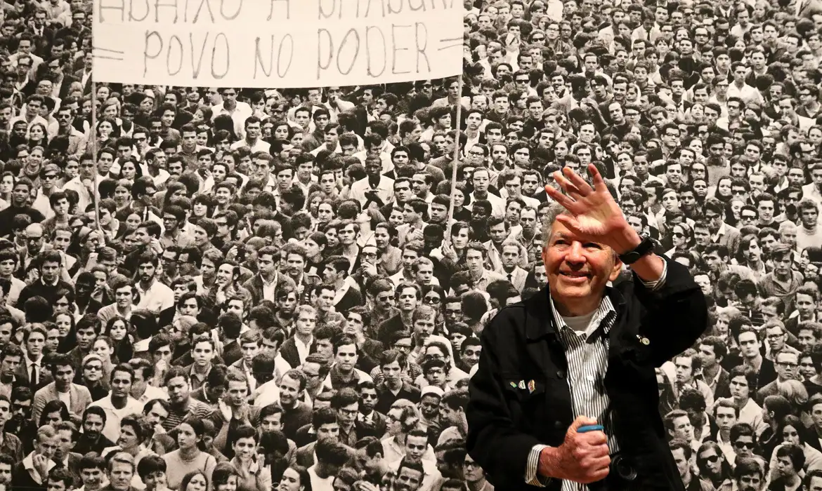 Evandro Teixeira em frente a uma de suas fotos da Ditadura Militar, a Marcha dos 100 mil/Foto: Tânia Rego