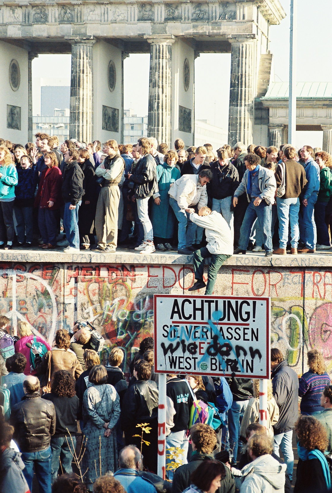 Transição ao capitalismo: Pessoas no topo do Muro de Berlim, em 9 de novembro de 1989. Foto: 