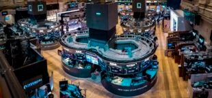 A Bolsa de Valores de Nova York é um espaço onde se realiza o lucro capitalista mediante o comprometimento do futuro. Foto de 2022, do salão principal de negociações. Tirada por Tobias Deml. Wikipedia.