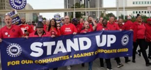 Membros do sindicato United Auto Workers marcham no centro de Detroit, em 15 de setembro de 2023, durante a greve "Stand Up" contra a Ford, a Stellantis e a General Motors. | Paul Sancya / AP